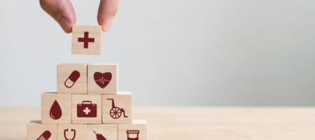 Someone is creating a pyramid stack of building blocks with health-related icons on them.