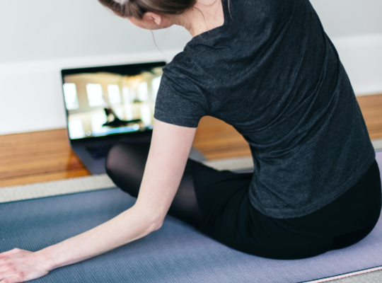 A person doing yoga stretches on a yoga mat on the ground.