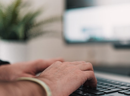 A close up of a pair of hands typing on a keyboard