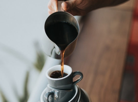 hand holding coffee and pouring on stacked cups