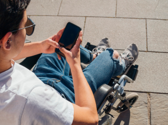 Person using a wheelchair looking at their smartphone