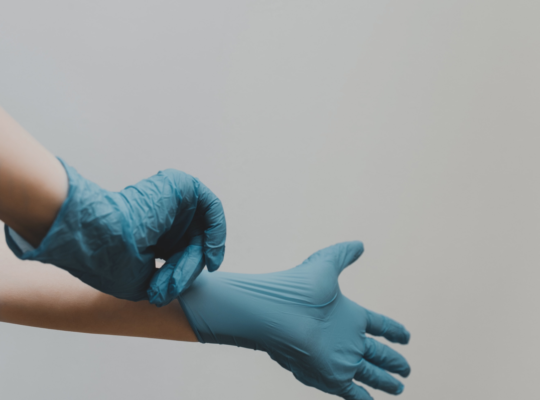 Medical worker putting on protective blue gloves