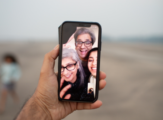 A hand holding up a phone on a video call with family members