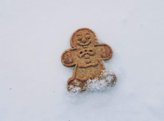 A gingerbread cookie lying flat on the snow.
