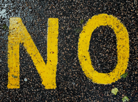 Photograph of the word No painted in yellow on an asphalt street