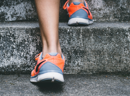 A person in running shoes walking up stairs