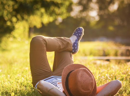 person lying down on the grass with the sun shining on them.