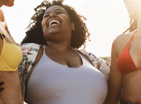 three people embrace at the beach with smiles on their faces