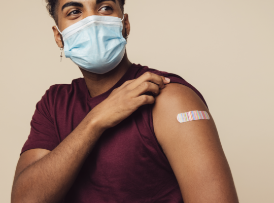 person showing off the bandaid on their arm after receiving a vaccine