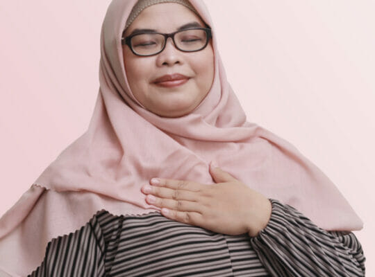 person smiling with a hand over their heart.